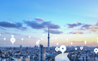 Smart city skyline with geospatial asset management location markers overlaying buildings and infrastructure at sunset.