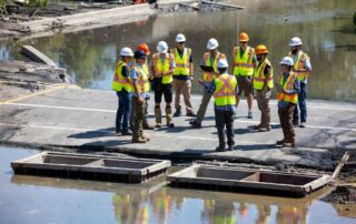 Public works team inspecting flooded municipal road and stormwater infrastructure after extreme weather event to inform climate resilience asset planning